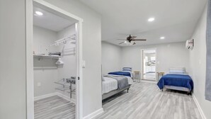 A modern bedroom with two beds, a ceiling fan, and a walk-in closet with shelves. - Apartamento en Bloomington (Bloomington)