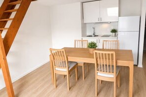A dining area with a wooden table and chairs, a small plant on the table, and a kitchen in the background. - Bright Duplex Near Grand Place • Self Check-in (Brussels)