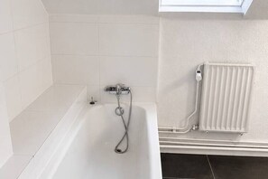 A bathroom with a bathtub, a shower, and a radiator. - Bright Duplex Near Grand Place • Self Check-in (Brussels)