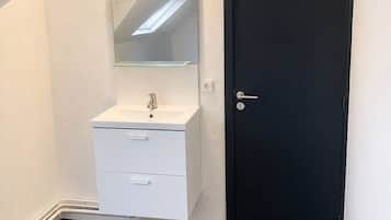 A bathroom with a white sink, a mirror, and a black door.