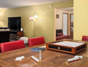 A wooden table with a Scrabble board, red chairs, and a lamp in a room with yellow walls. - Private Mountain Chalet | Timberline | Mt. Rainier (Packwood)