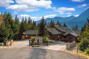 Un chalet avec une entrée en pierre, plusieurs pièces et une vue sur les montagnes.