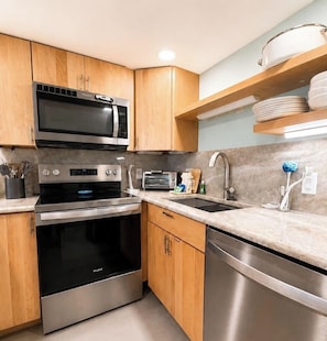 A modern kitchen with stainless steel appliances, wooden cabinets, and a marble countertop.