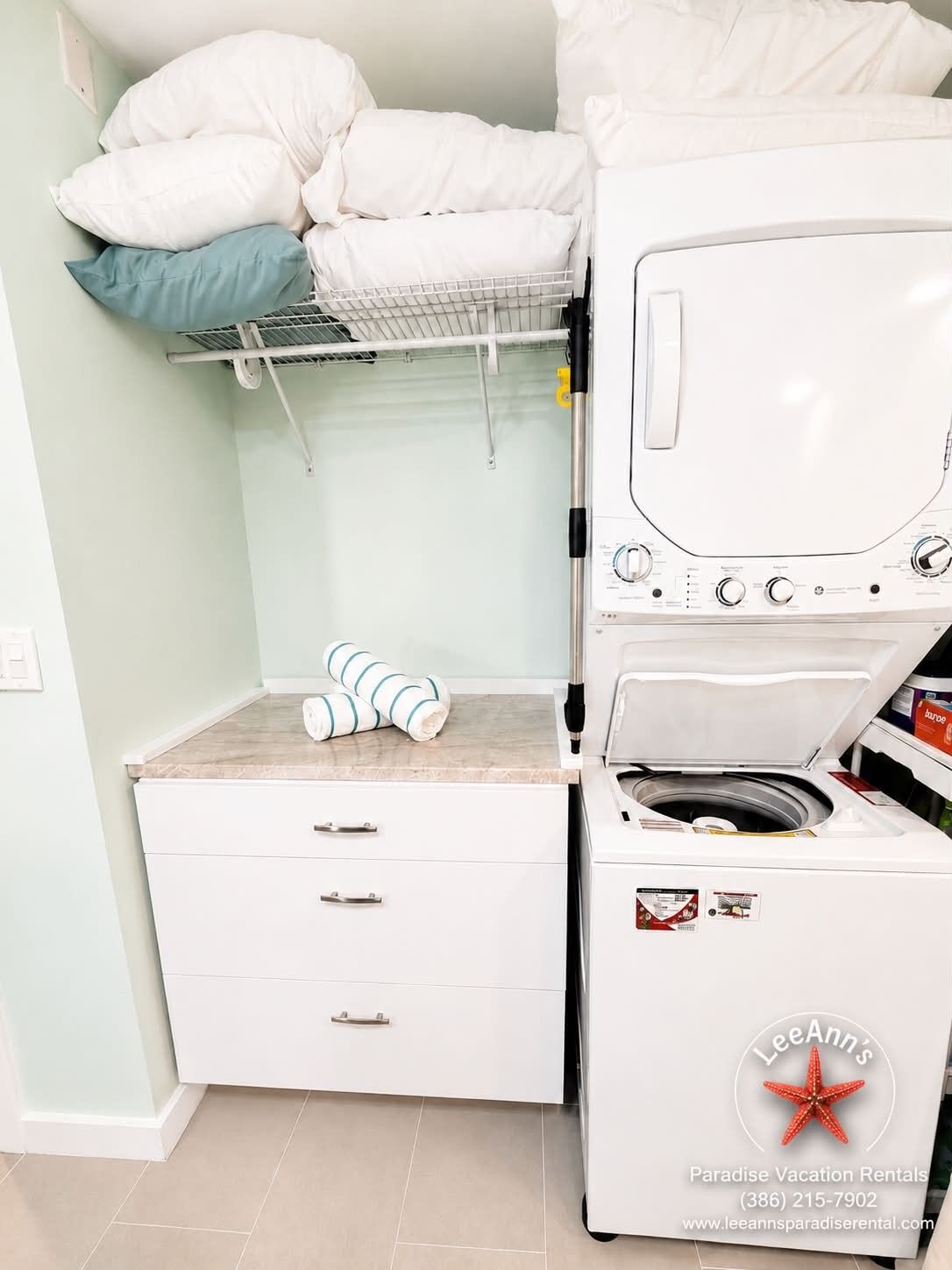 A laundry area with a washing machine, a drying rack, and a storage cabinet.