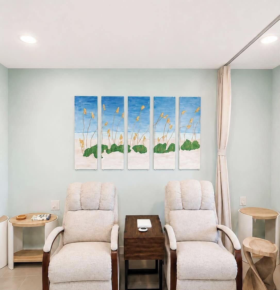 A room with two armchairs, a small wooden table, and a wall-mounted painting.
