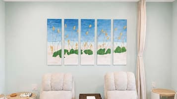A room with two armchairs, a small wooden table, and a wall-mounted painting.