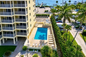 A multi-story hotel with a rooftop pool, a parking area, and a view of the marina.
