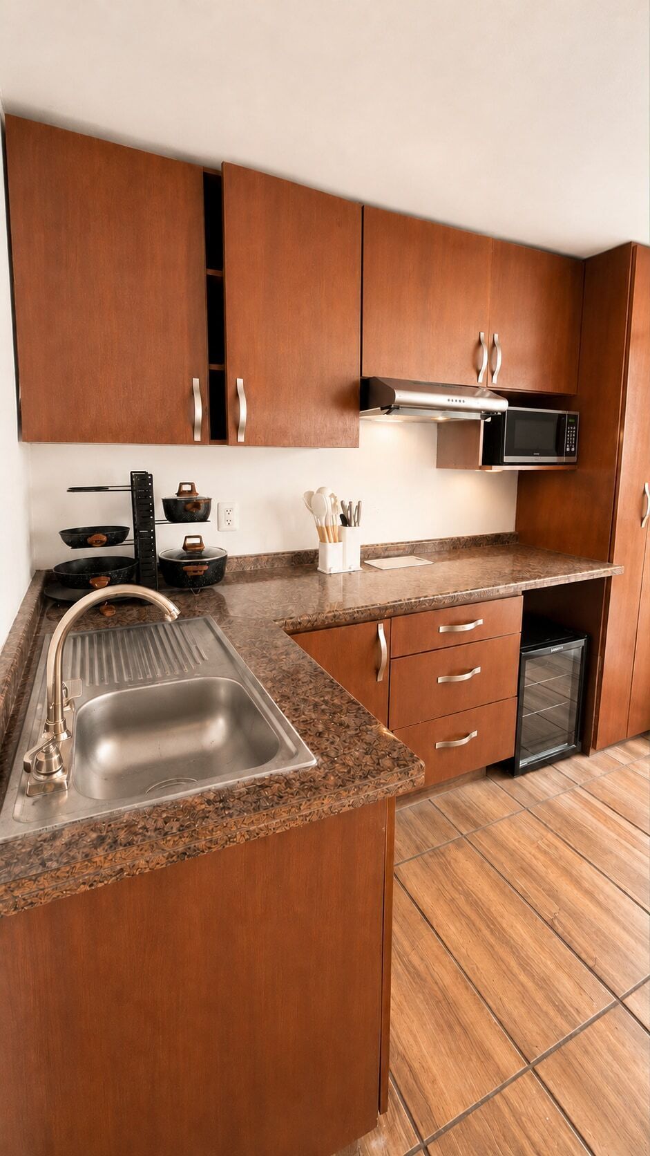 A kitchen with wooden cabinets, a stainless steel sink, a microwave, and a dishwasher.