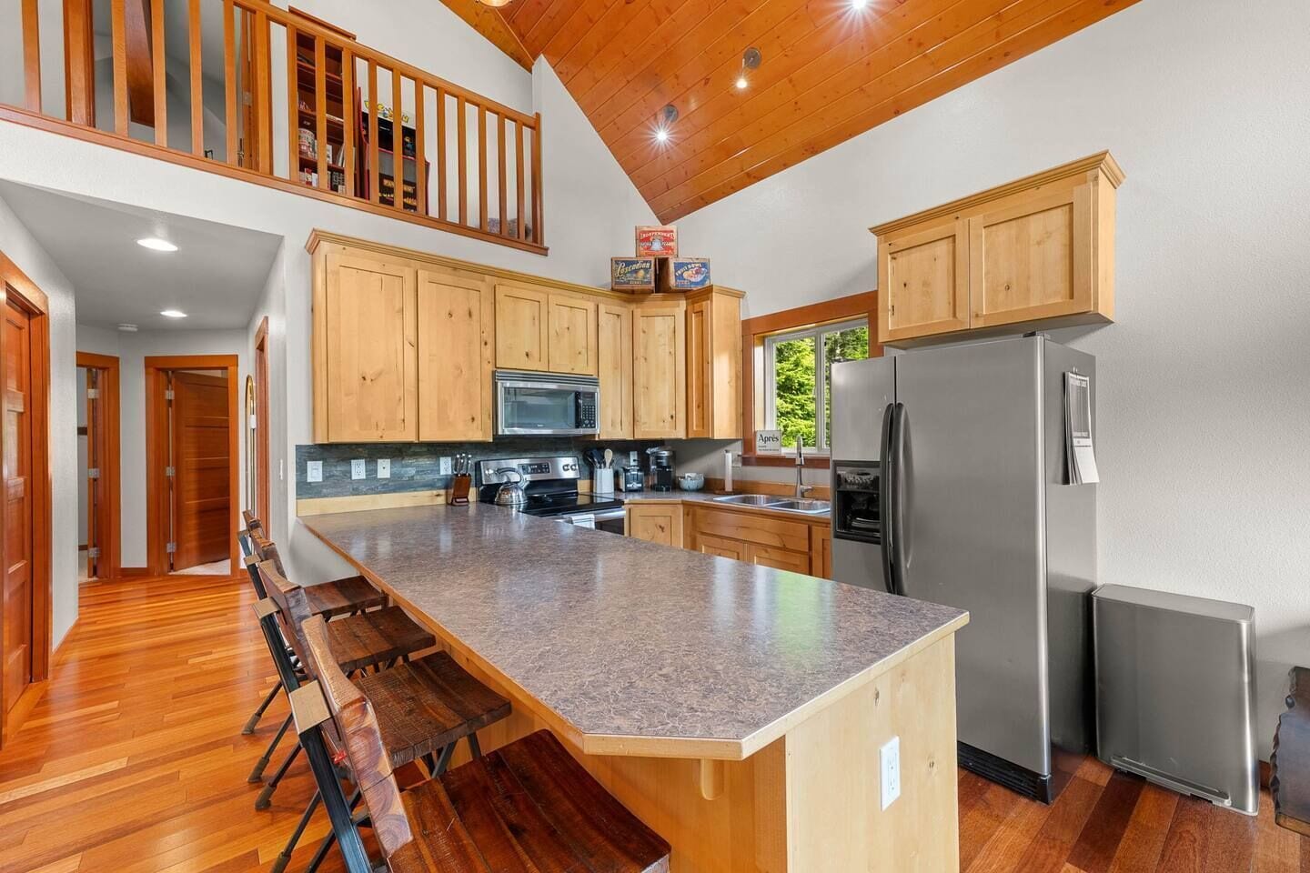A spacious kitchen with wooden cabinets, a granite countertop, stainless steel appliances, and a dining area with benches.