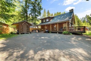 A cabin with a gravel driveway, a covered porch, and a wooden deck. - River Rock Retreat | Hot Tub+A/C | Mt Rainier (Packwood)