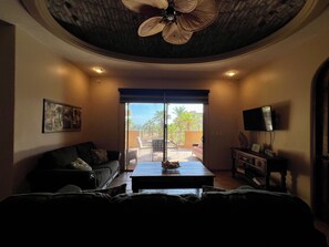 A living room with a sofa, a coffee table, a television, and a ceiling fan. - Bella Sirena B-202 (Puerto Peñasco)