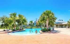 Une piscine bordée de palmiers et un espace abrité avec des chaises.