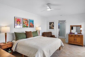 A hotel room with a bed, bedside tables, a wardrobe, a ceiling fan, and artwork on the walls. - Canyon Sands Beauty (Palm Springs)
