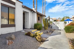 Una propiedad residencial con fachada blanca, un camino de hormigón y un jardín de cactus.