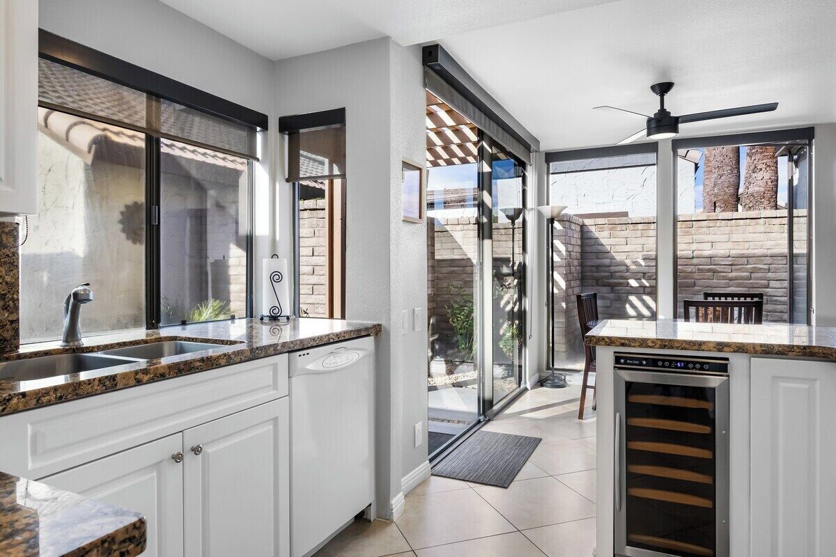 A modern kitchen with a built-in dishwasher, a large window, and a sliding glass door leading to an outdoor area.
