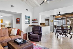 Amplia sala de estar con un sillón reclinable de cuero, una mesa de comedor con sillas y una cocina al fondo.