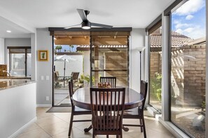 A modern dining area with a round table, chairs, and a ceiling fan. - Canyon Sands Beauty (Palm Springs)