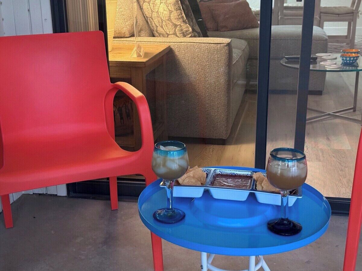 En rød stol og et blåt bord med to glas af en brun drik samt en bakke med mad.