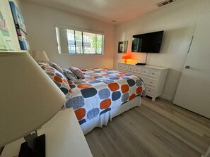 Ein Schlafzimmer mit einem Bett, einem Schminktisch, einem Fernseher und einem Fenster.