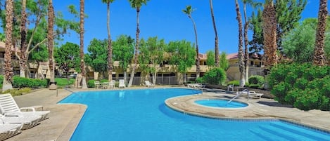 A swimming pool with lounge chairs and palm trees.
