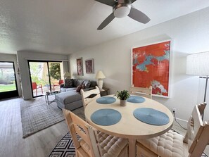 Ein modernes Wohnzimmer mit Essbereich, Deckenventilator und einem großen abstrakten Gemälde an der Wand.