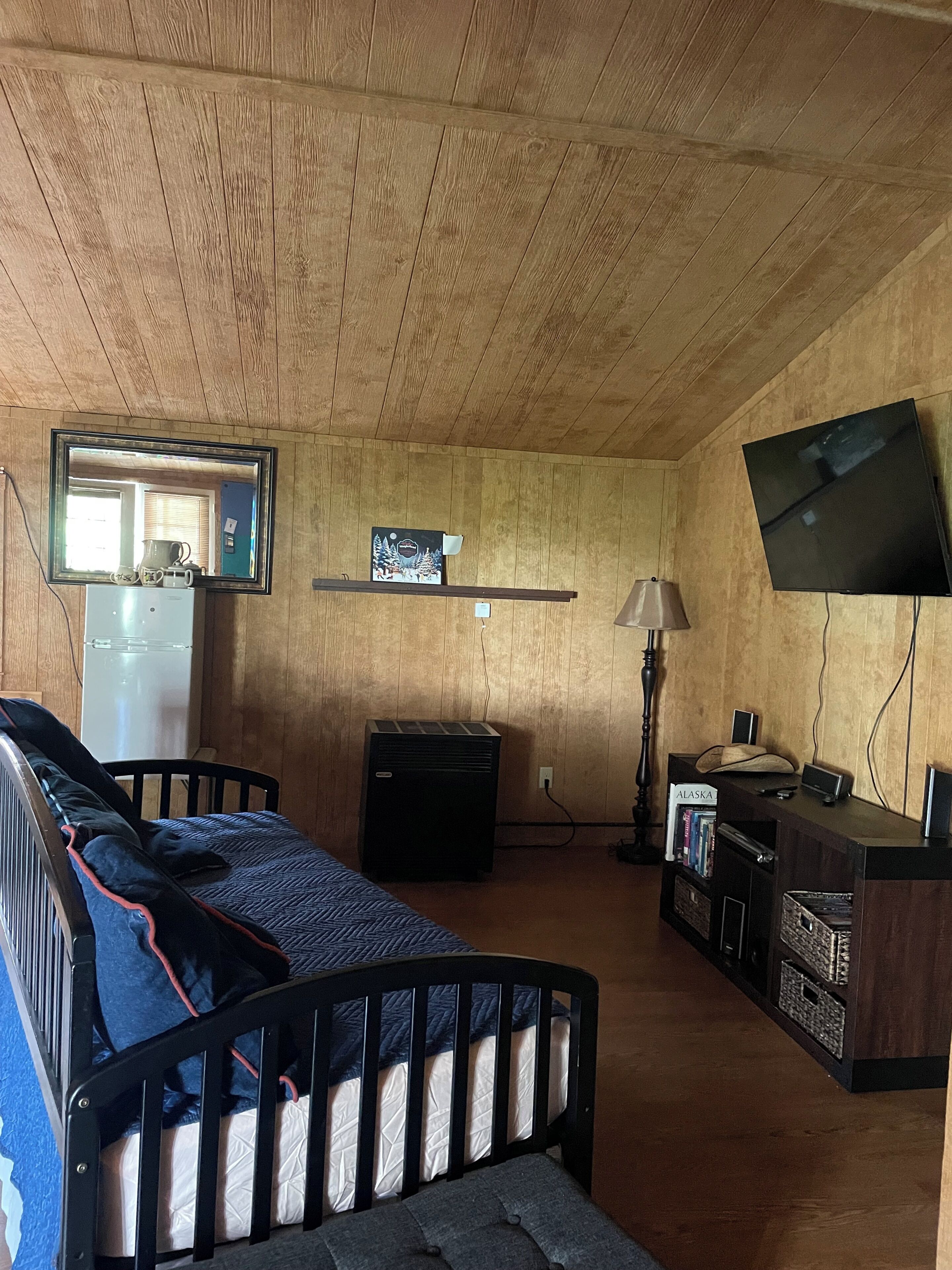 Une chambre avec un lit, un bureau, une télévision et un miroir.