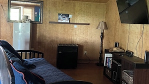 Quarto com uma cama, escrivaninha, televisão e espelho.