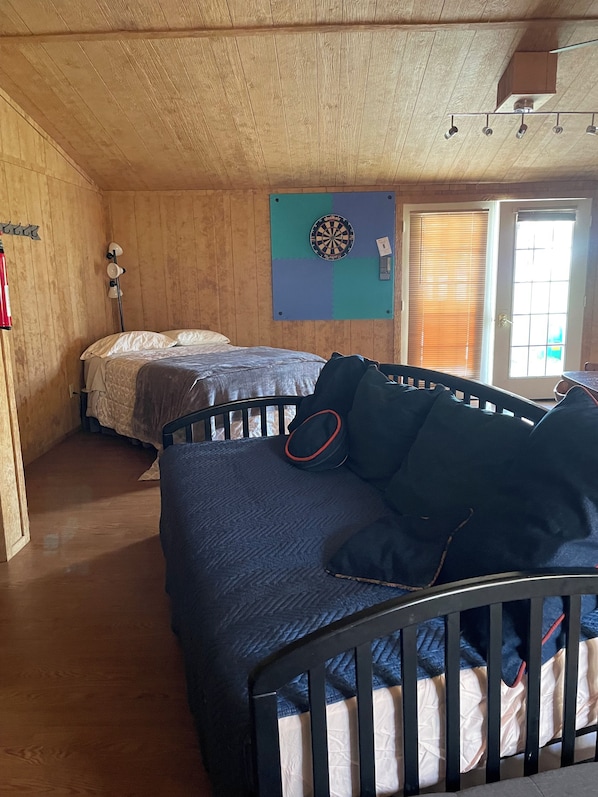 Habitació amb llit, bressol, joc de daus i finestra amb persianes.