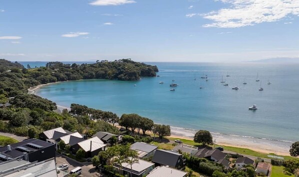 A coastal residential area with houses, a beach, and boats on the water.