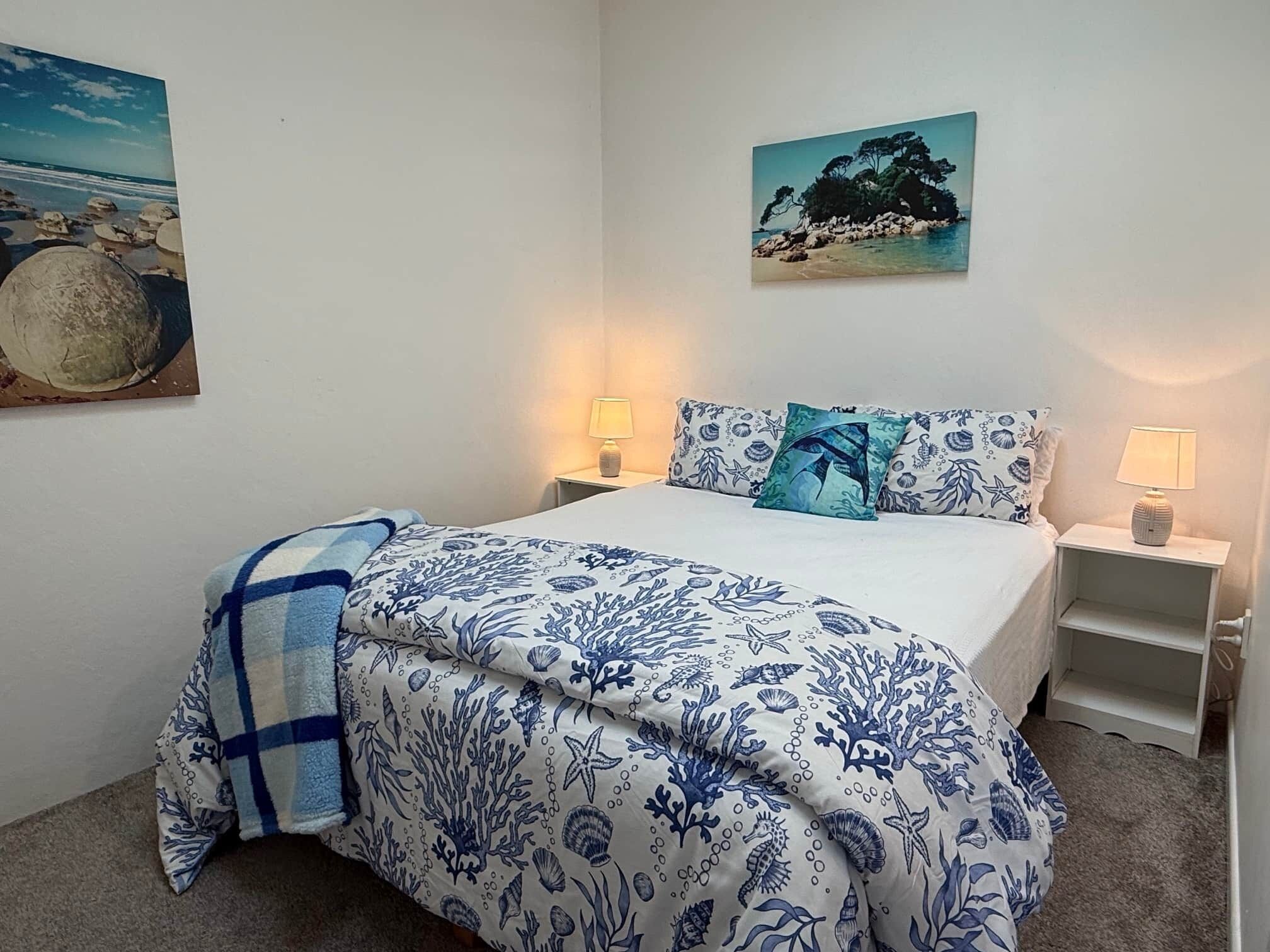 Ein Schlafzimmer mit einem Bett, zwei Nachttischen, einer Lampe und zwei an der Wand hängenden Bildern.
