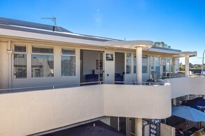Ein modernes Gebäude mit Balkon, großen Fenstern und einer flachen Dachfläche.