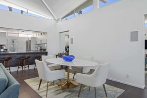 Eine moderne Küche mit weißen Schränken, einer zentralen Kochinsel und einem Essbereich mit rundem Tisch und Stühlen.