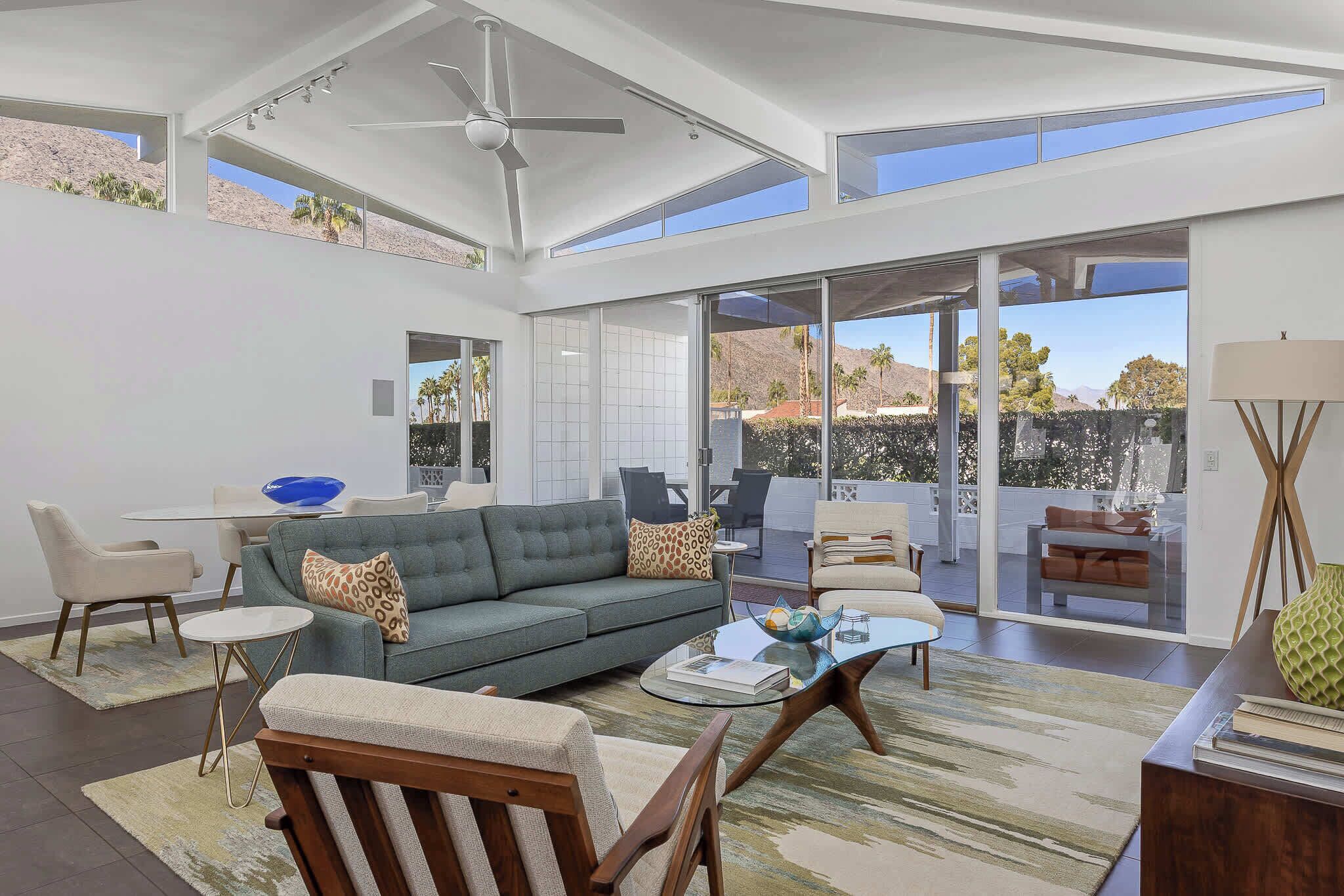 A spacious living room with a high ceiling, a ceiling fan, and a large sliding glass door leading to an outdoor patio.