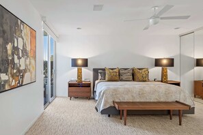Ein Schlafzimmer mit einem Bett, Nachttischen, einem Deckenventilator und einem großen abstrakten Gemälde.