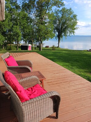 A deck with wicker furniture and a view of a lake.
