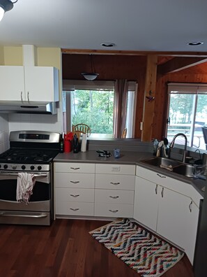 A modern kitchen with a stove, oven, and white cabinetry. - Quiet Lakefront paradise near Sheguiandah, ON. (Northeastern Manitoulin And T*)