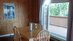 Una stanza con rivestimento in legno, un tavolo da pranzo e sedie, un lampadario e una finestra con tende.