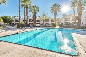 A swimming pool with lounge chairs and palm trees, surrounded by buildings. - PS Golf & Tennis Club Condo (Palm Springs)