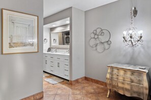 A bathroom with a white vanity, a mirror, a chandelier, and a framed picture on the wall. - Canyon Granada Hideaway (Palm Springs)