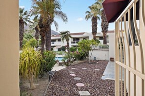 Un patio con palmeras, una piscina y un edificio con balcones.