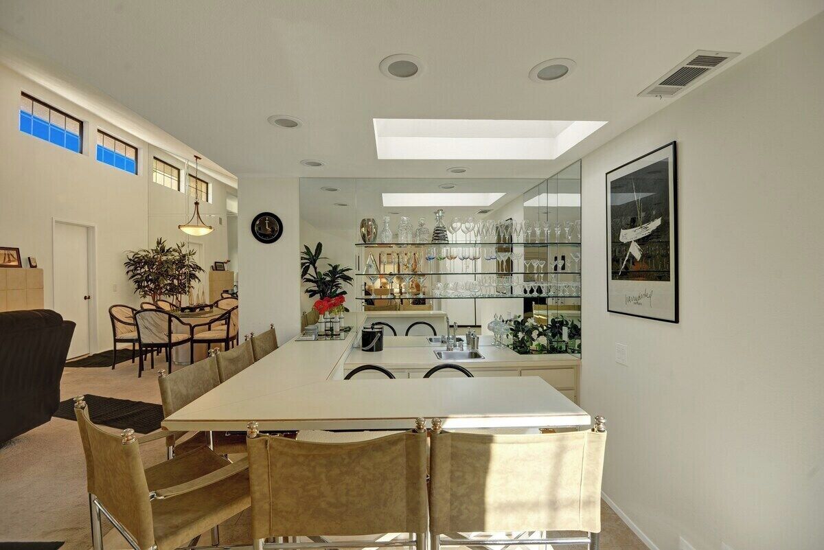 Un espace repas comprenant une longue table, des chaises et une vitrine en verre où sont exposés divers objets.