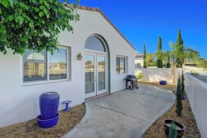 Een modern huis met een terras, een barbecue en een groot raam.