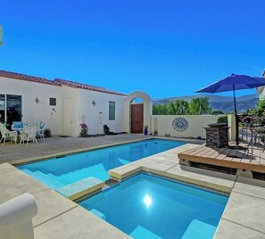 Une piscine avec un espace patio, du mobilier d’extérieur et une vue sur les montagnes.