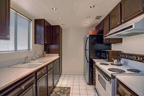 A compact kitchen with a sink, stove, microwave, and refrigerator. - Ramon Estados Treehouse (Palm Springs)