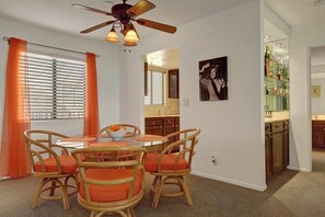 A dining area with a round table and chairs, a ceiling fan, and a kitchen in the background. - Ramon Estados Treehouse (Palm Springs)
