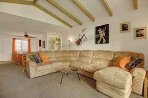 A living room with a large L-shaped sectional sofa, a coffee table, and a ceiling fan. - Ramon Estados Treehouse (Palm Springs)