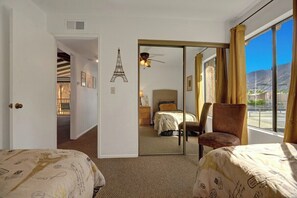 A hotel room with a bed, a chair, a mirror, and a view of the outside. - Ramon Estados Treehouse (Palm Springs)