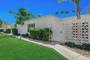 A residential area with a white building, a gated entrance, and a well-maintained lawn. - Garden Villas Paradise (Palm Springs)