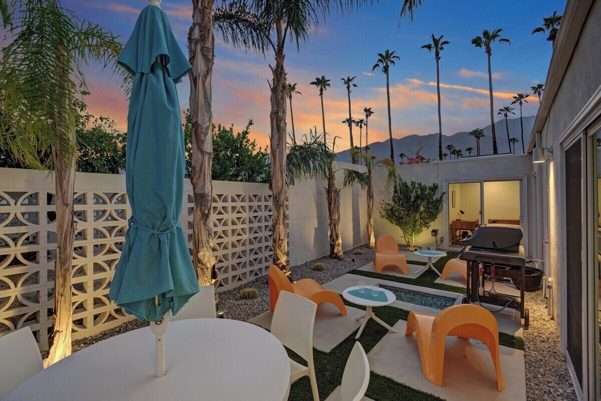 An outdoor patio with a pool, seating, and a barbecue area.