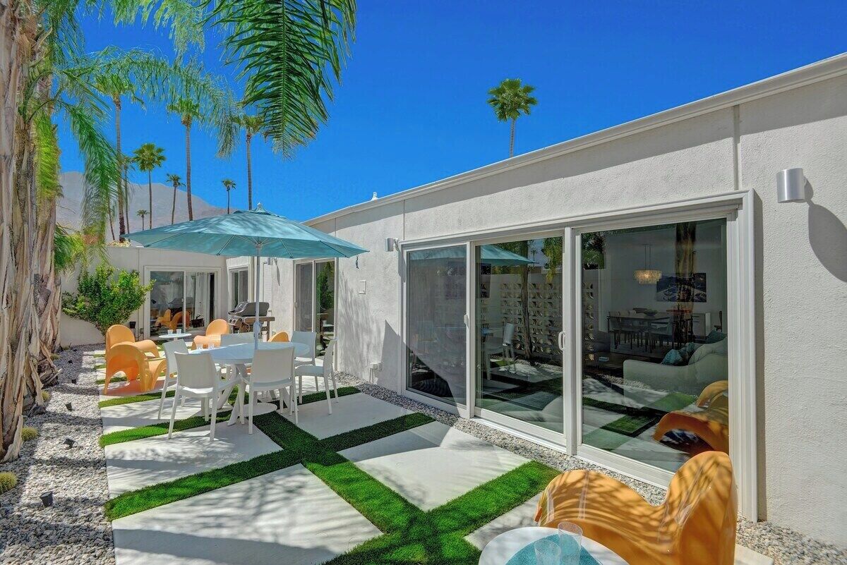 A modern patio with a dining table, chairs, and a blue umbrella.
